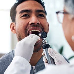 A dentist screening a patient for oral cancer