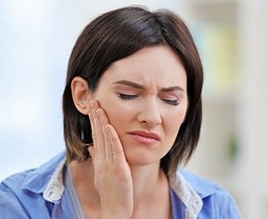 Woman holding cheek in pain