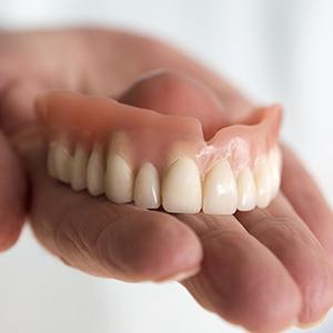 Hand holding full denture