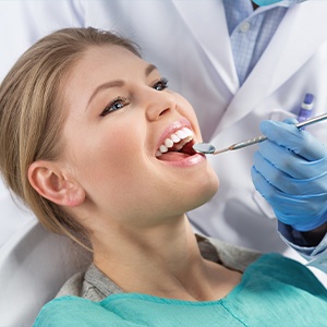 A woman is getting her teeth checked by an dentist.