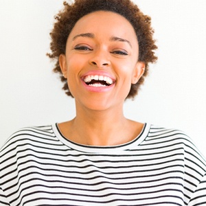 A woman with short hair is smiling and wearing a striped shirt.