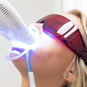 A woman is getting her teeth cleaned by an electric toothbrush.