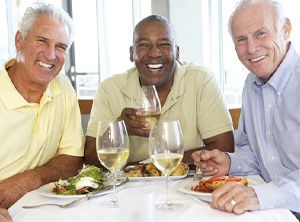 Three men sitting at a table with plates of food.