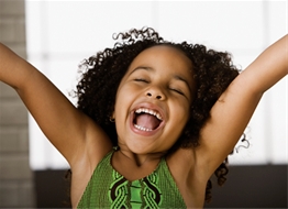 A young girl is laughing with her arms raised.