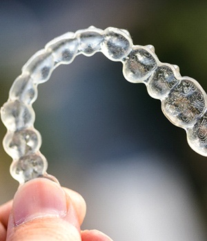 A person holding onto an invisible aligner