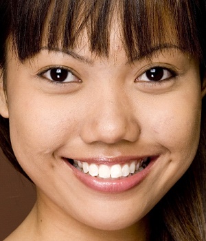 A woman with brown hair and white teeth smiling.