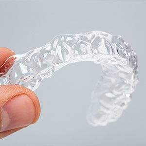 A person holding an invisible orthodontic appliance.