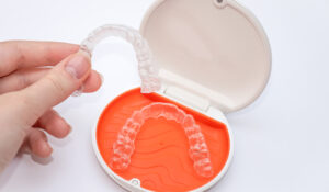 A person putting their teeth into an orthodontic appliance.