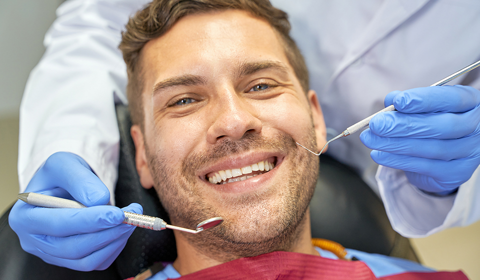 A man smiling while getting his teeth cleaned.